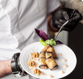 waiter-holding-plate-fried-aubergine-wraps-with-walnuts 1